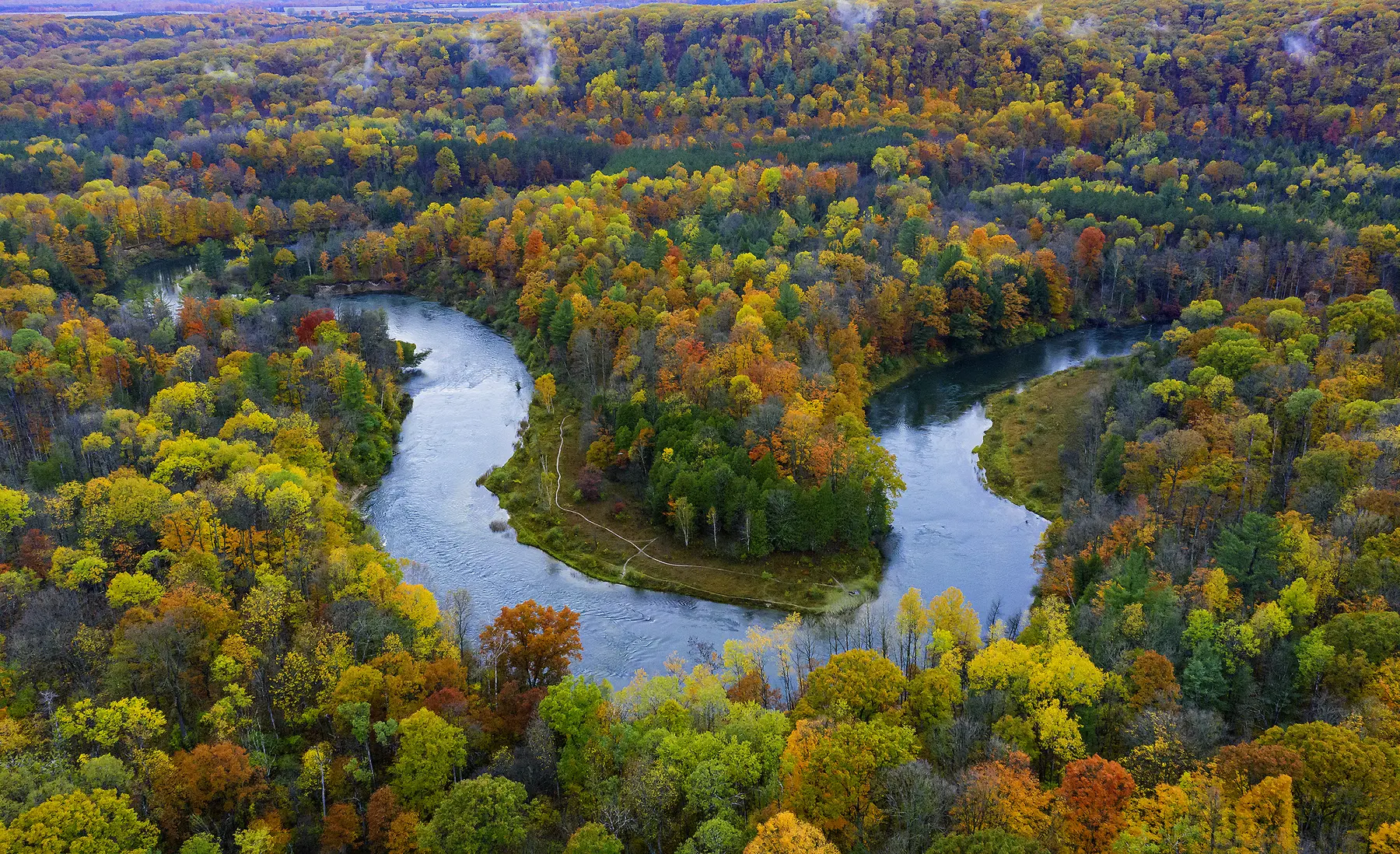 The Manistee River winding through a forest in fall color